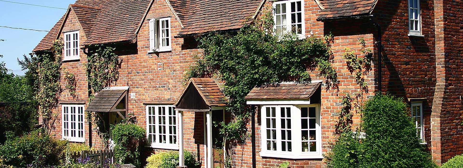 Large brick home with white aluminium windows Maidstone and trees growing on front of house