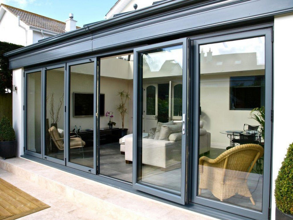 Bi-fold doors Kent opening up into a conservatory with sofa and rattan furniture